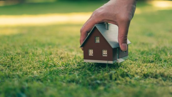 A hand is holding a model house